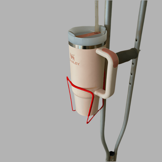 Cup holder attached to crutches with a pink cup featuring a brand logo.