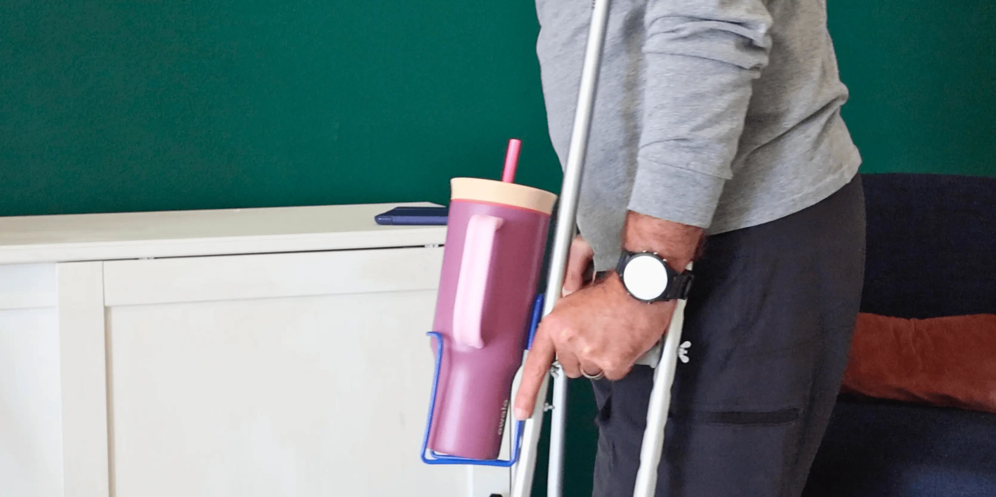 Translation missing: en.Person using crutches with a pink cup attached, against a green wall