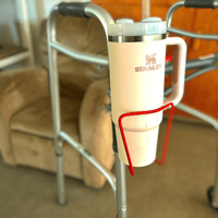 Walker cup holder securely holding a Stanley drink mug, designed for walkers, made of lightweight aluminum for convenience.